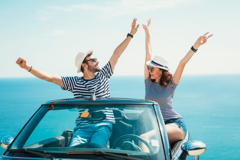 un un jeune couple de mariés heureux dans une voiture décapotable en bord de mer profite d'un de leur cadeaux de mariage de type voyage