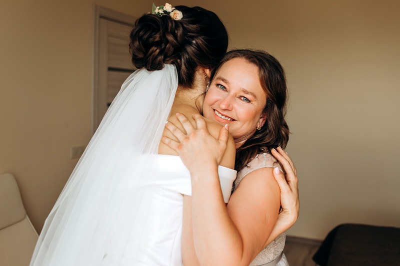 Une maman enlace tendrement sa fille à son mariage pour la féliciter, illustration cadeau de mariage par la présence