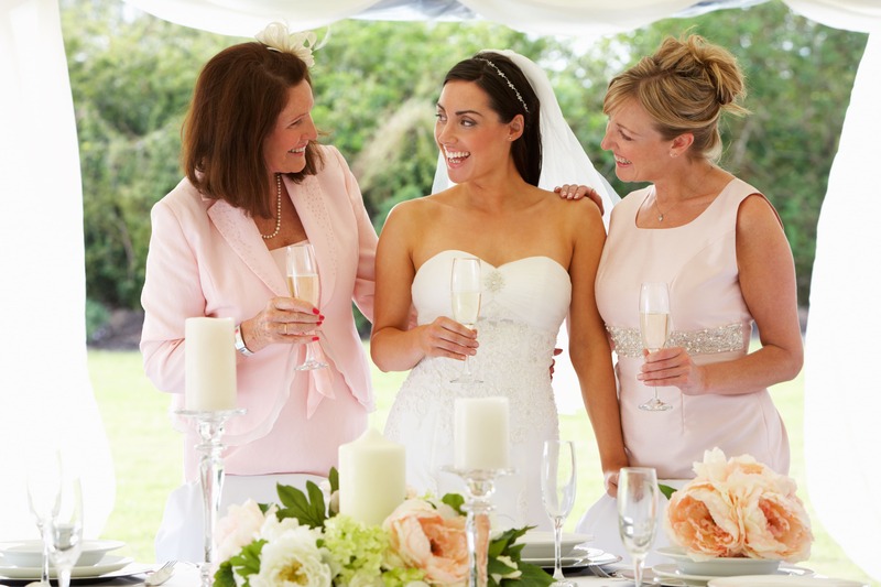 une jeune mariée à son mariage, vêtue de blanc, entourée de sa mère et de sa belle-mère est émue par leur présence qui est l'un des plus beaux cadeaux de mariage