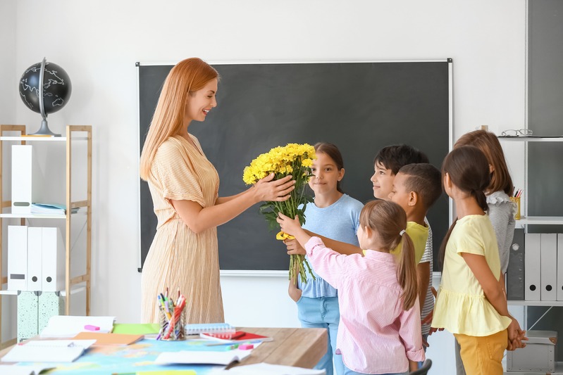 des enfants offrent des fleurs à leur maîtresse d'école comme cadeau de fin d'année
