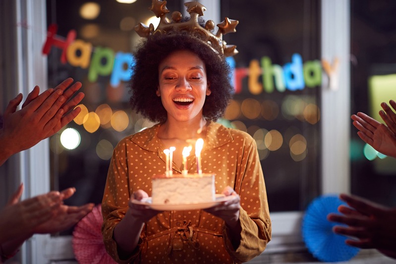 une femme souffle les bougies de son gâteau d'anniversaire lors de la célébration entre amis et va recevoir un cadeau commun