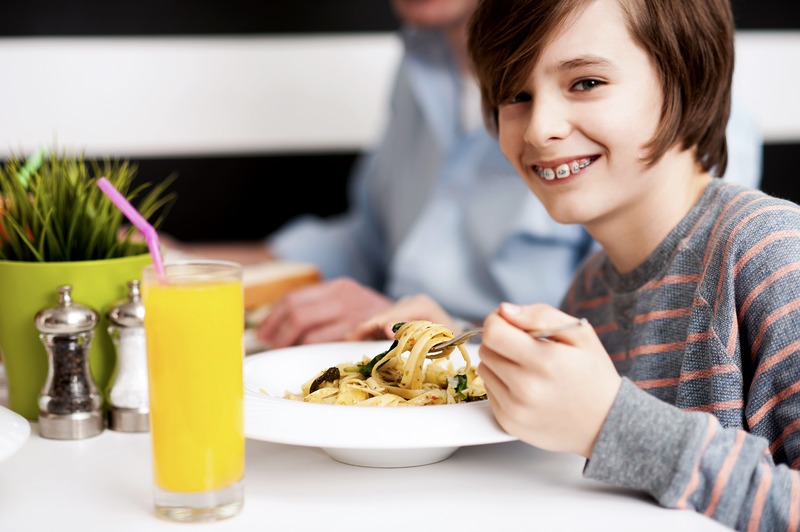 jeune garçon souriant profite d'un repas au restaurant lors d'une sortie père-fils