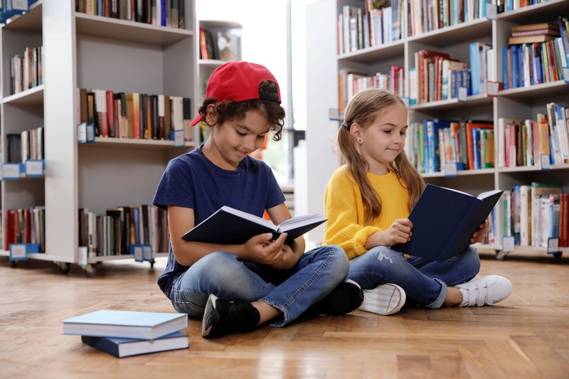 un garçon et un fille occupés à lire des livres à la bibliothèque parmi les activités à faire à paris pendant les vacances scolaires