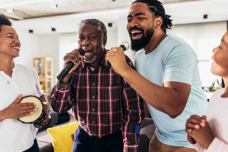 une famille s'amuse et deux hommes chantent lors d'un karaoké chez eux, lors d'un cadeau surprise offert a un homme chanteur et fan de musique