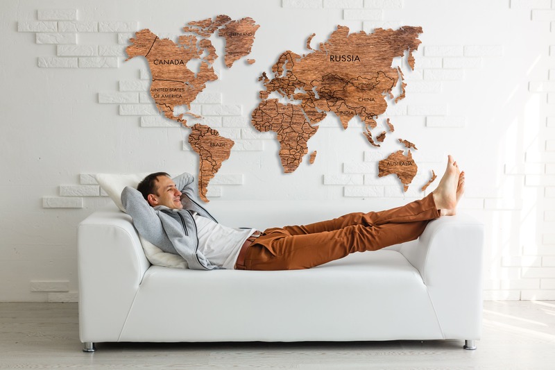 un homme allongé sur son canapé avec une map monde cadeau décorative affichée sur le mur