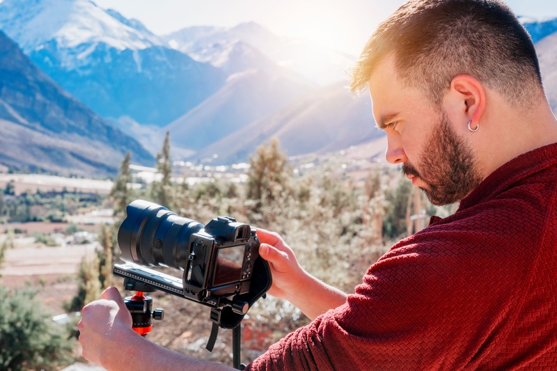 un homme et son appareil photos devant un paysage montagneux
