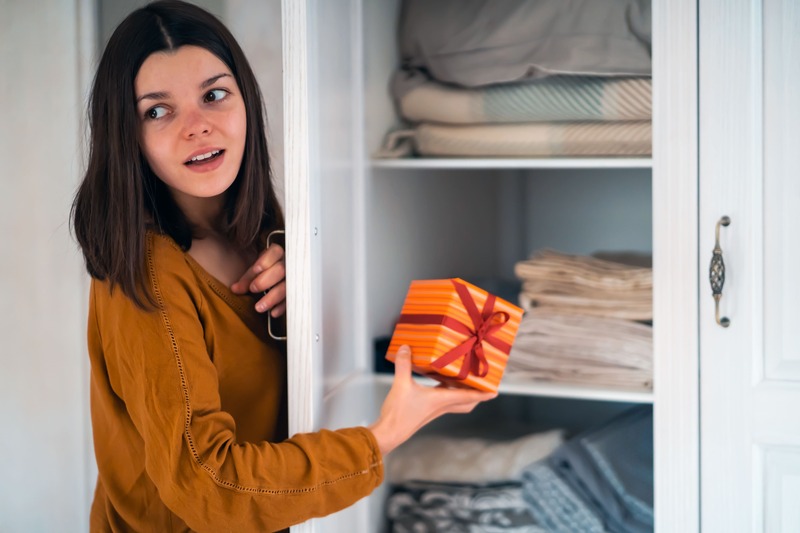 une jeune femme cache la carte cadeau qu'elle va offrir dans la maison pour effectuer une surprise au fêté