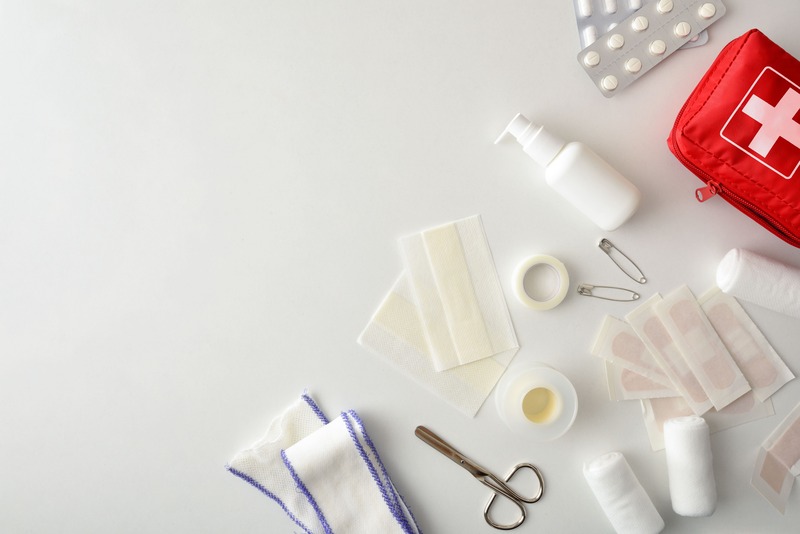 visuel des éléments à mettre dans une trousse d'urgence et kit de santé à préparer dans check list vacances spéciale santé : ciseau, pansements, antiseptique, anti-douleurs 