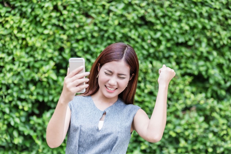 une-femme-heureuse-trouve-son-cadeau-carte-cadeau-caché-en-geocaching-dans-le-jardin en extérieur
