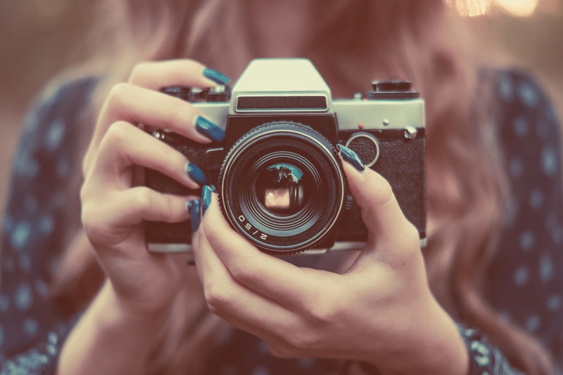 une main de femme manucuré qui tient en main un appareil photo vintage