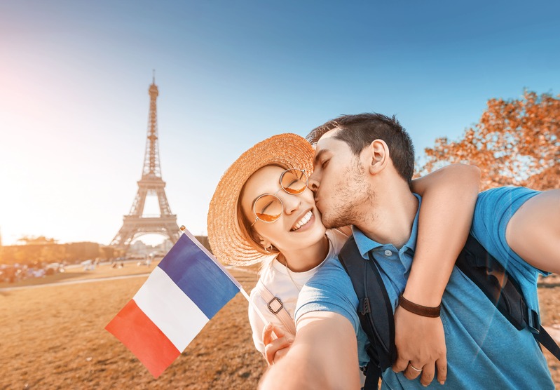 Couple de jeune mariés amoureux en lune de miel en France à Paris, arborant un drapeau français avec vue sur la tour Eiffel