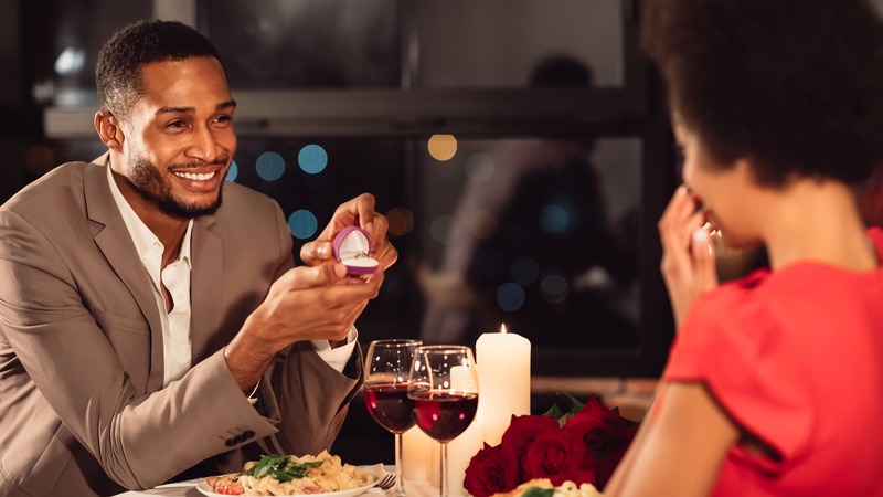 une femme vêtue de rouge qui accepte une demande au mariage au restaurant